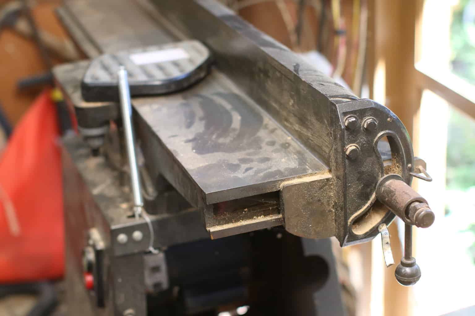 A jointer covered in sawdust sits in a workshop