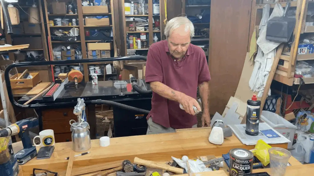 Man spraying a can of shellac over wood