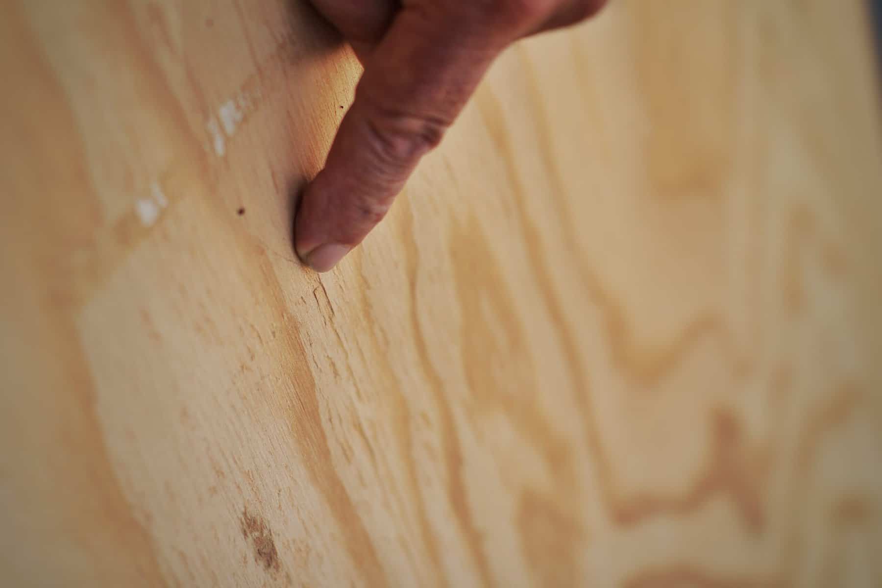 A close-up view of a finger pointing at the crack in the wood