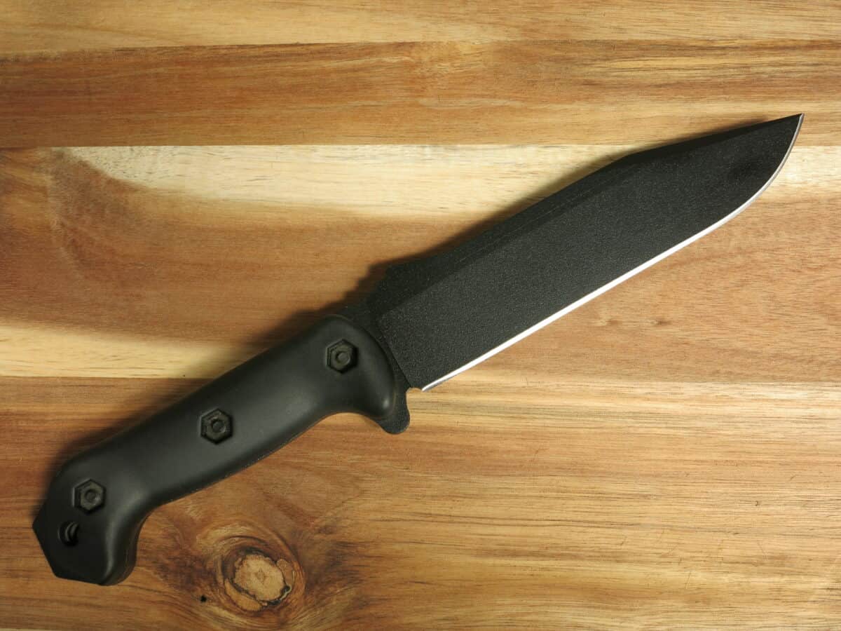 A black utility knife on a wooden board